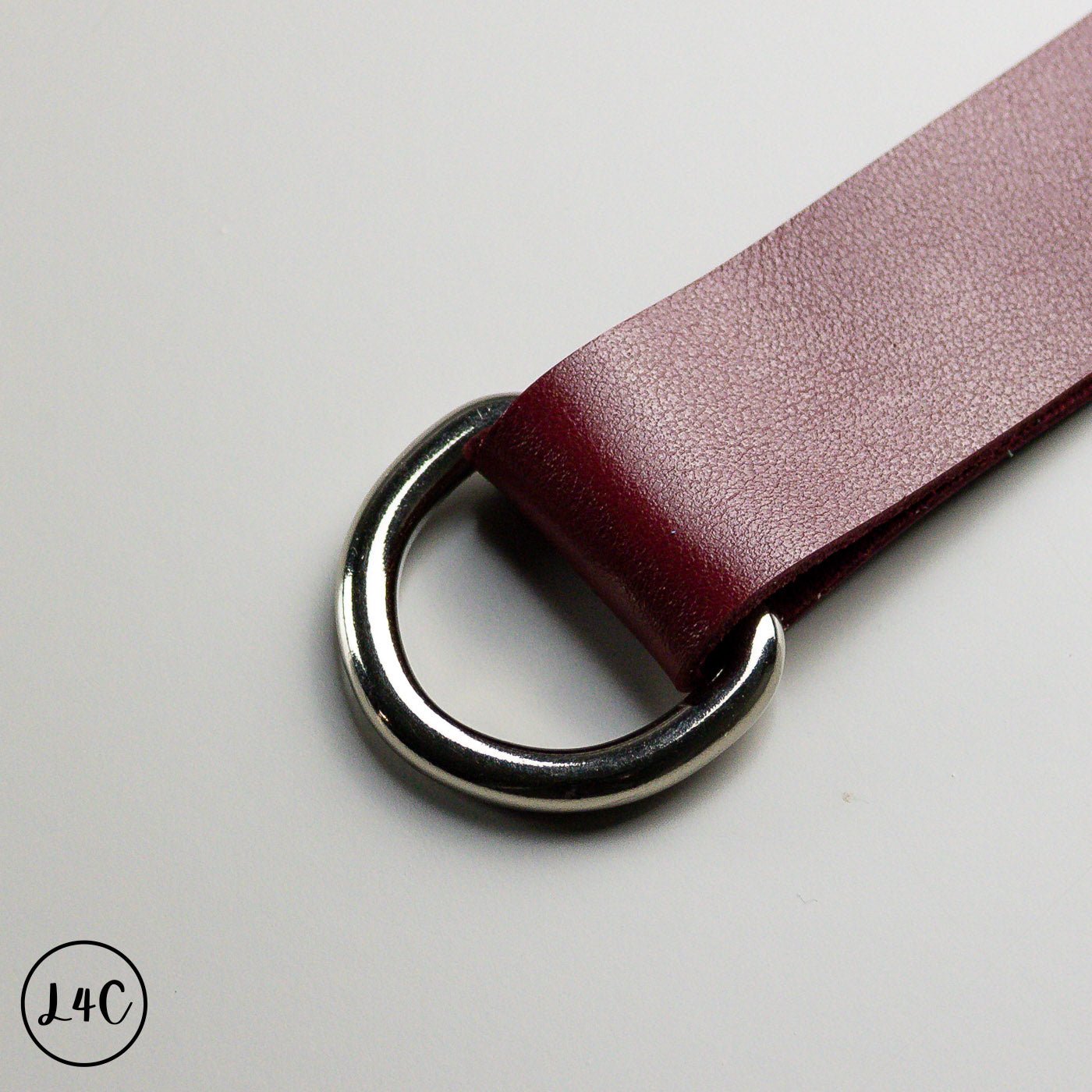 Close-up of a red leather belt with a silver buckle on a light gray background