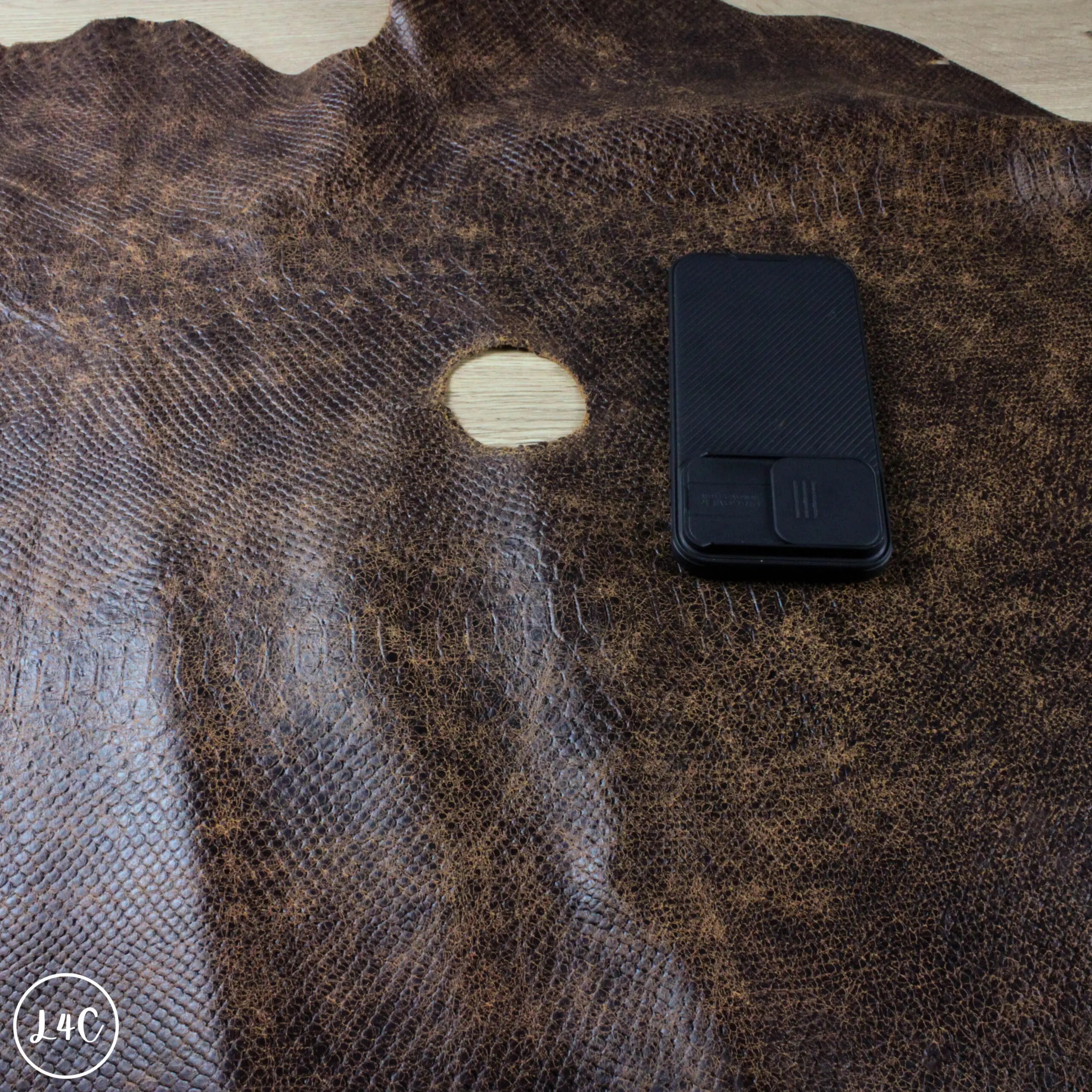Distressed Antique Brown, Snake Print Textured Leather with iphone 15 pro max next to a hole