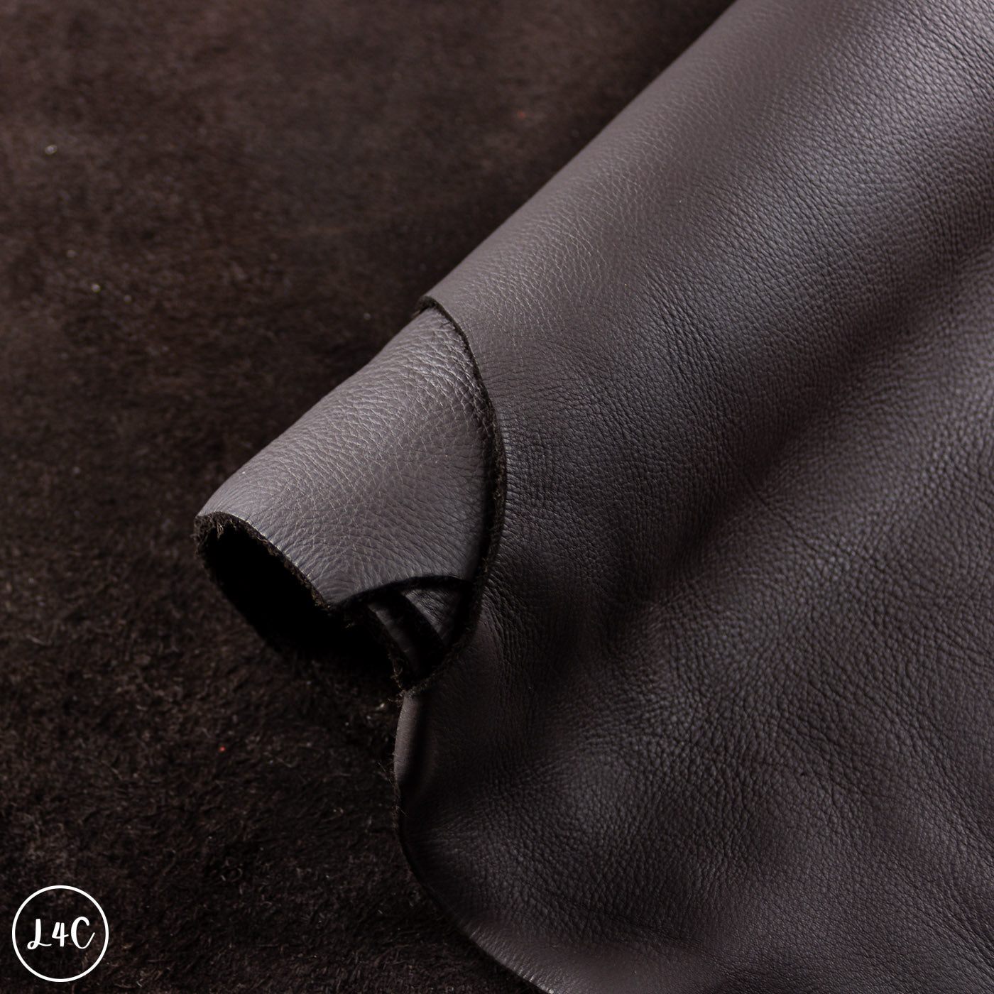 Close-up of black leather fabric with a visible brand logo in the corner.