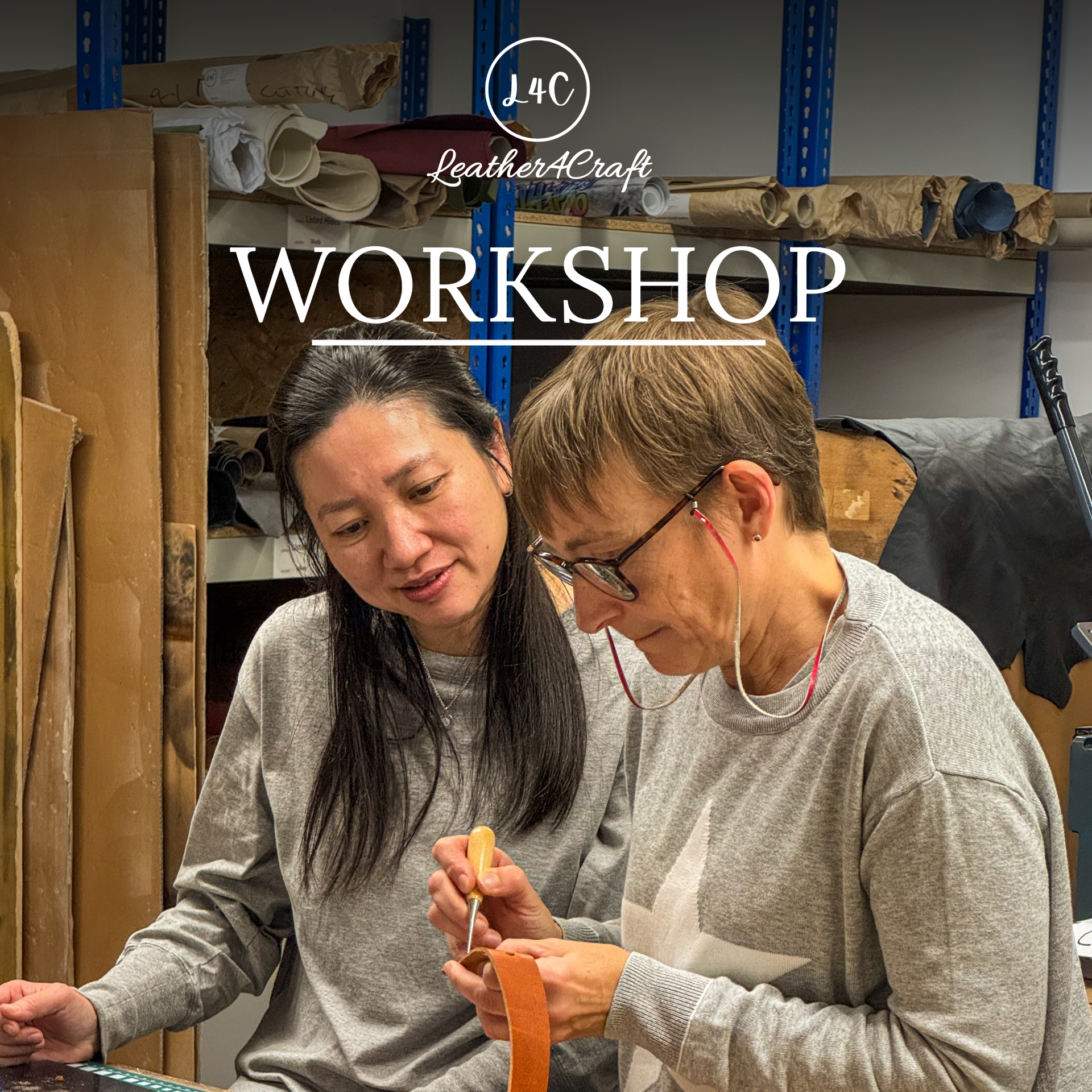 Two women collaborating in a leather workshop, with one holding a piece of orange leather and a small tool.