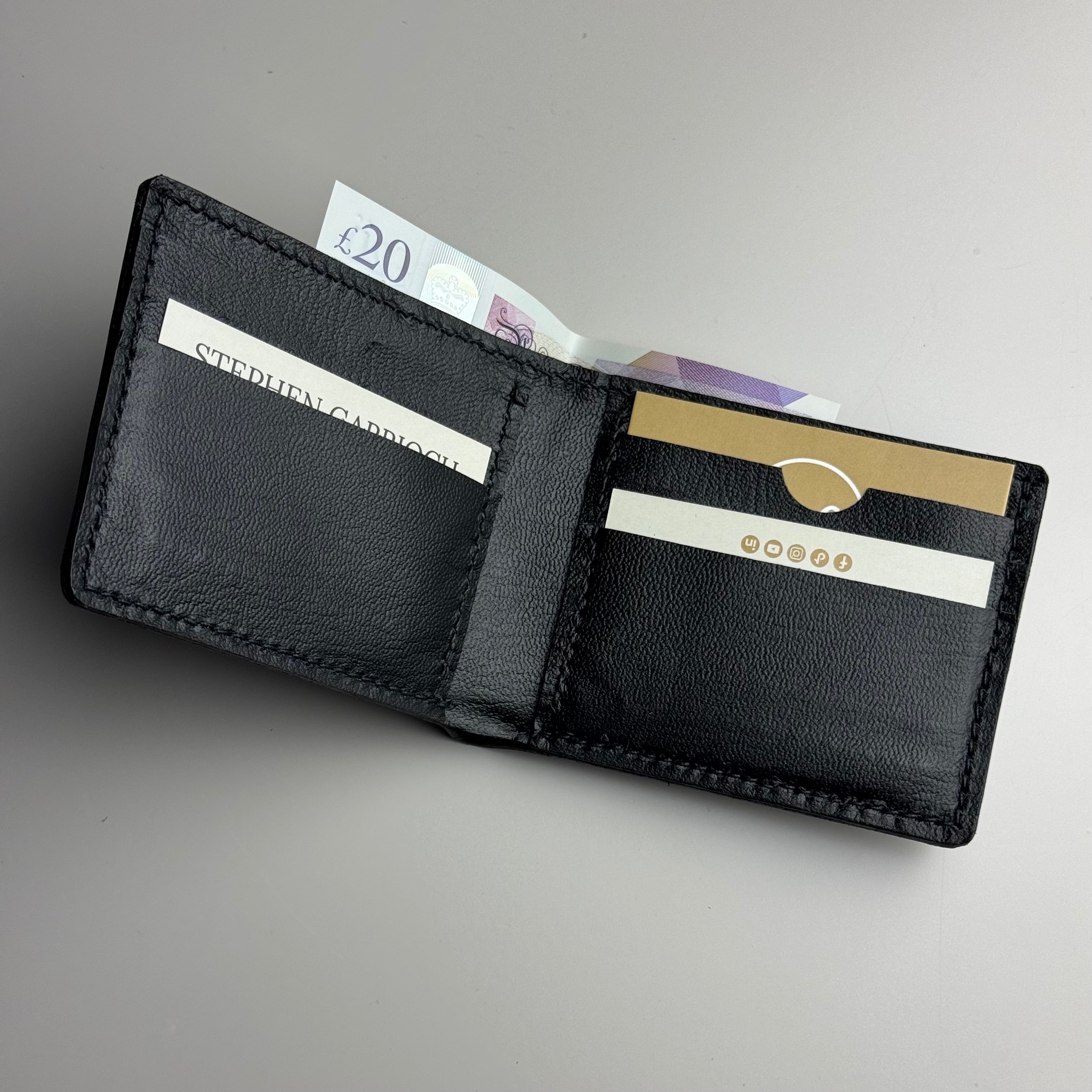 Black leather wallet with cards and money on a gray background