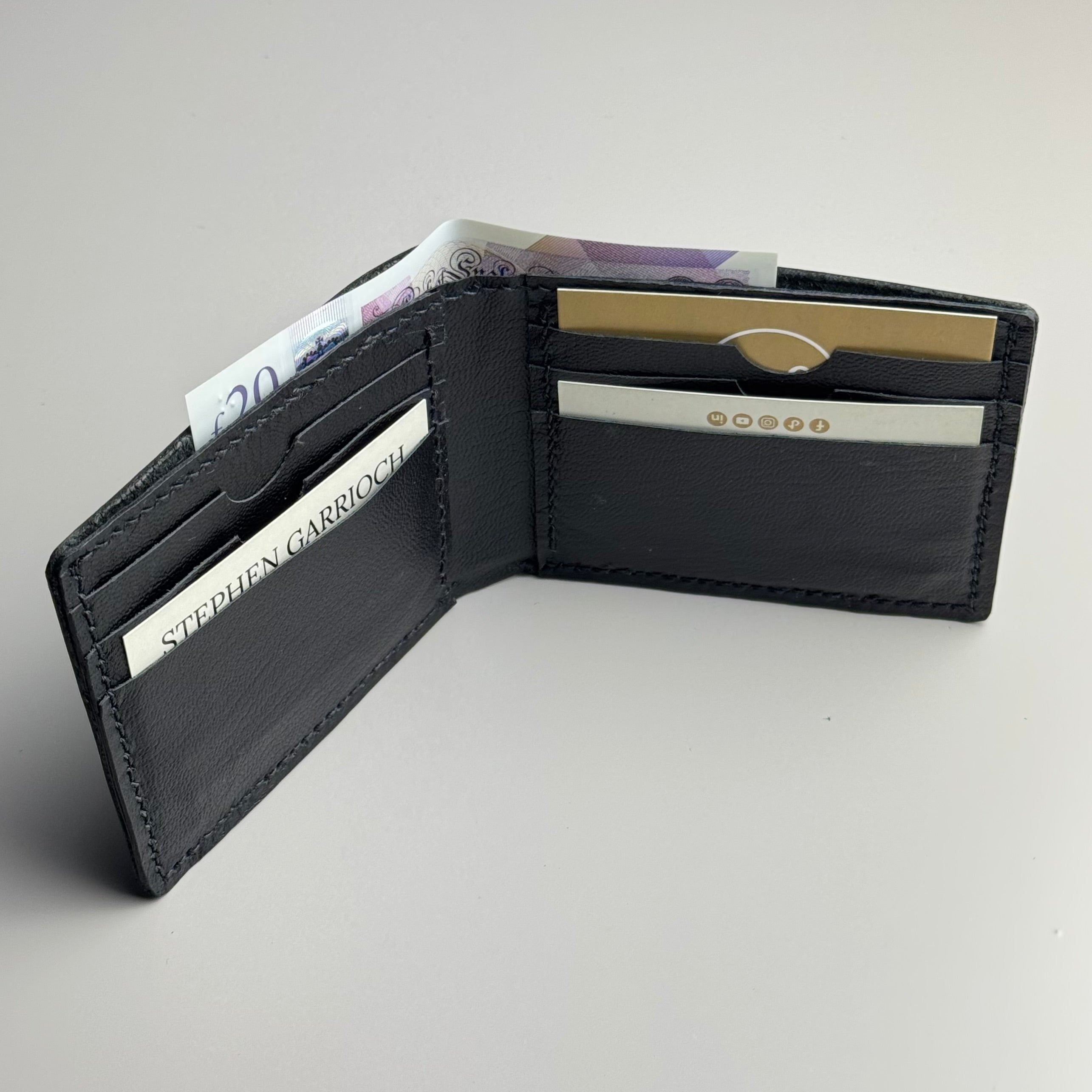 Black leather wallet with money and cards on a light gray background