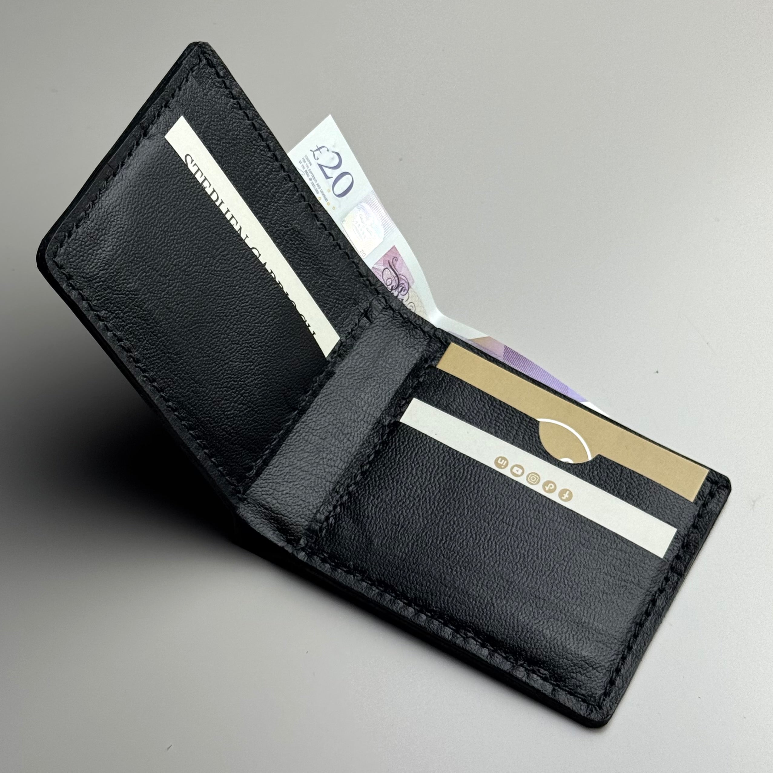 Black leather wallet with cards and money on a gray background