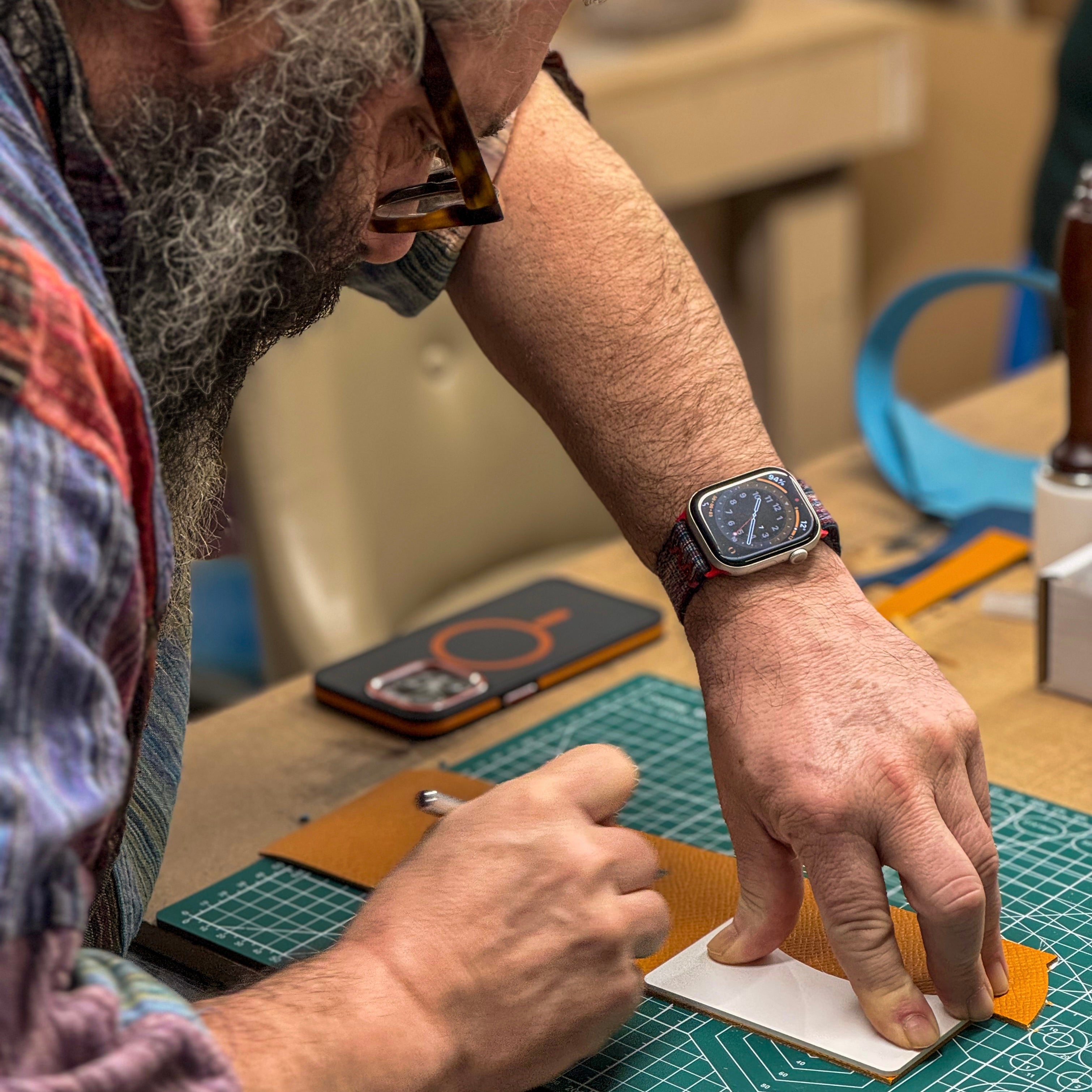 Man working on a craft project with a watch on his wrist, surrounded by tools and materials.