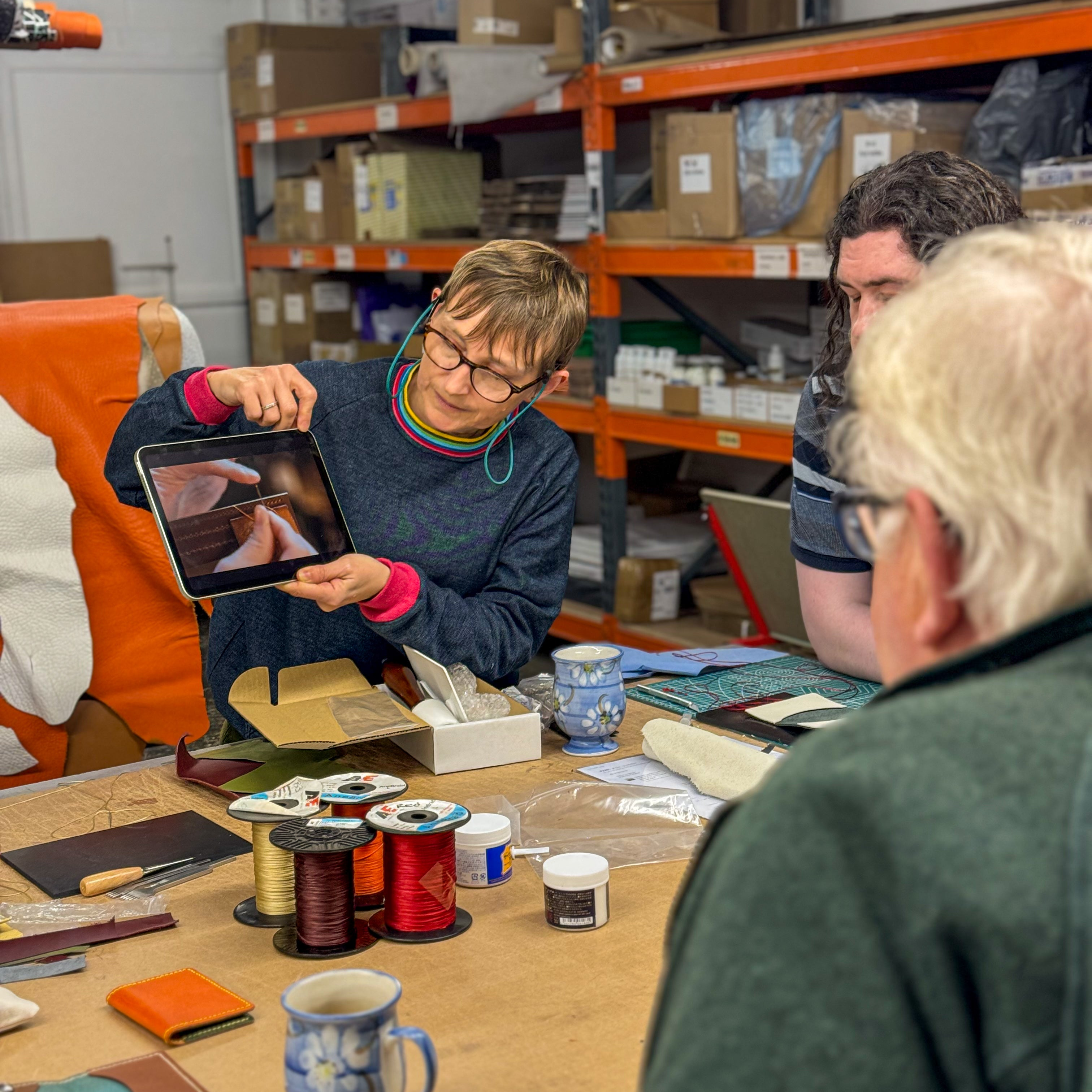 Person using a tablet in a workshop setting with others around