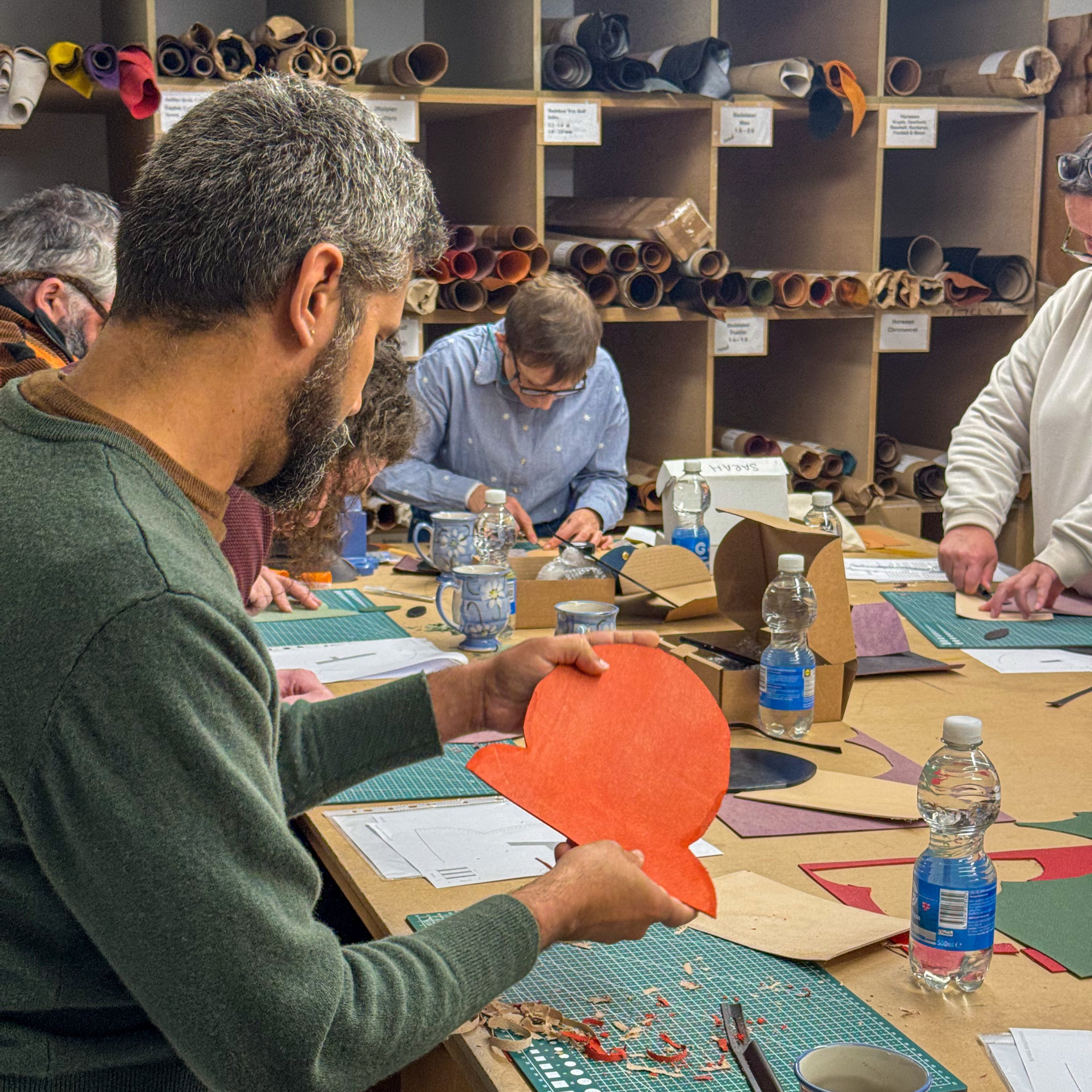 Group of people working on a craft project in a room with shelves of materials.