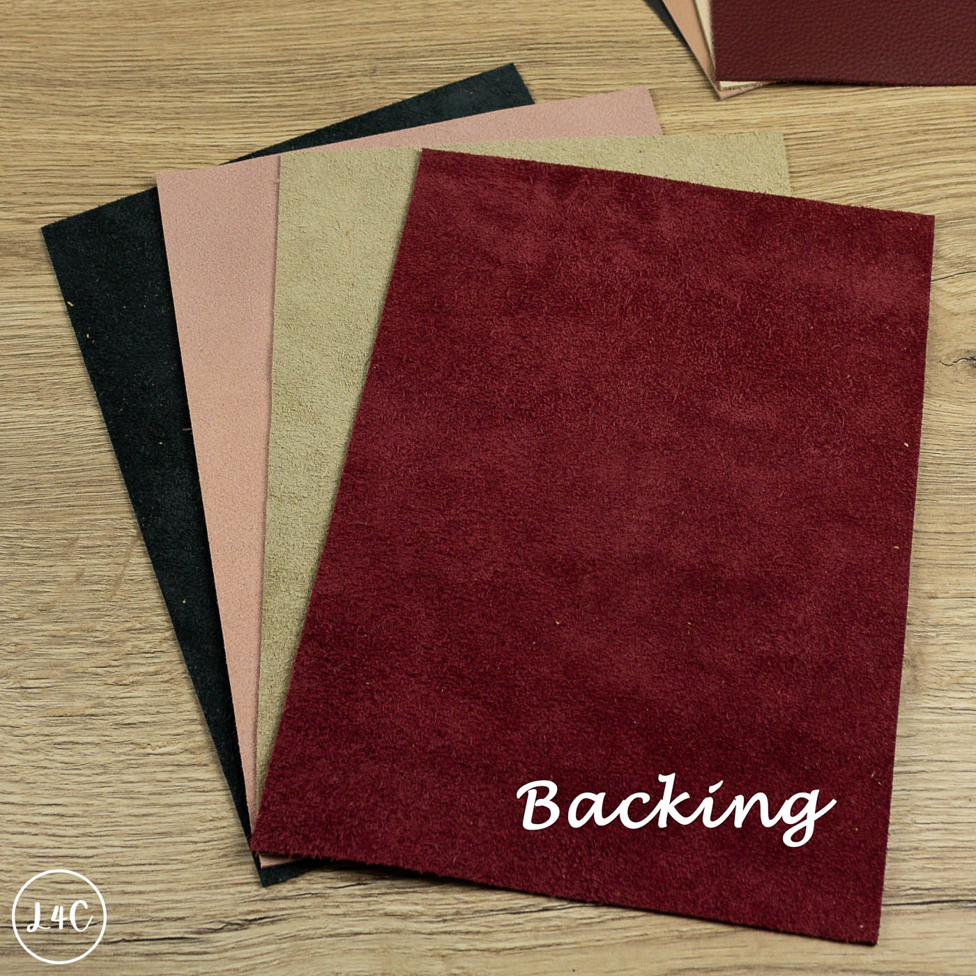 Collection of different leather sheets with 'Backing' text on a wooden surface
