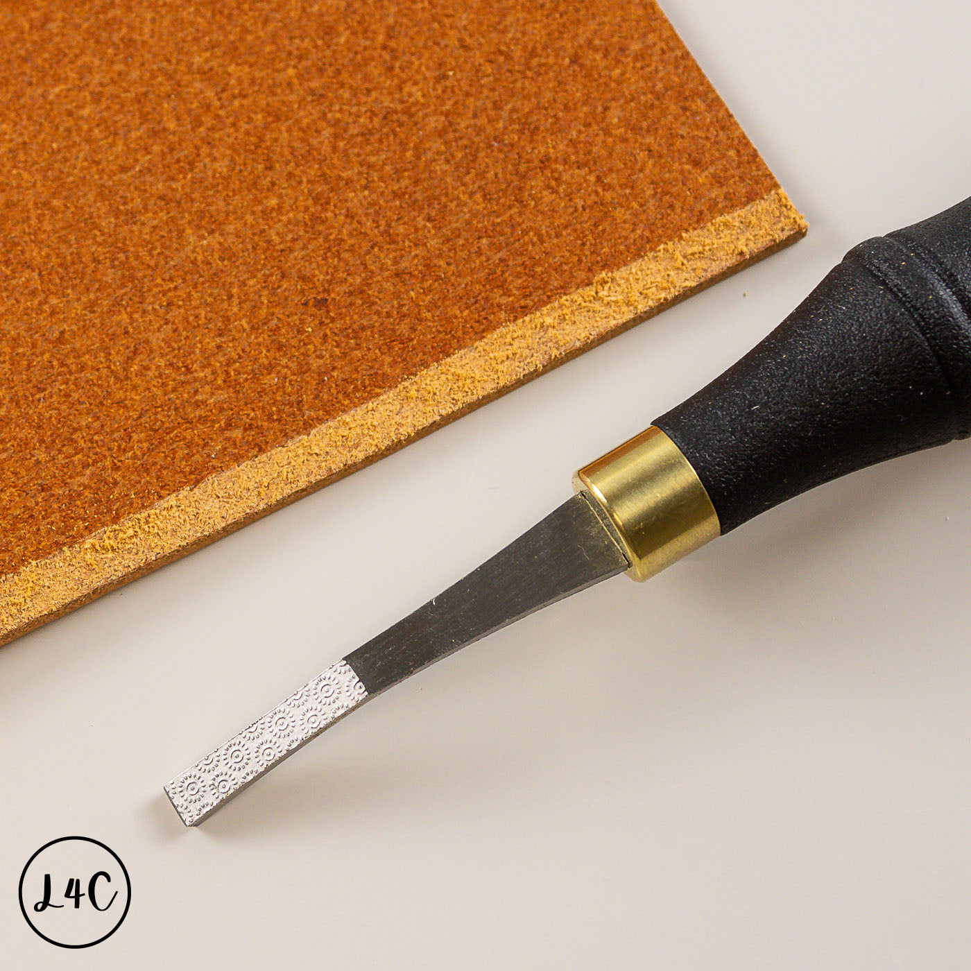 tool with black handle and brown leather on a white surface