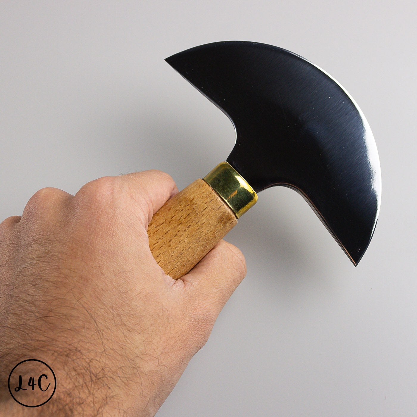 Hand holding a round knife with a wooden handle against a gray background