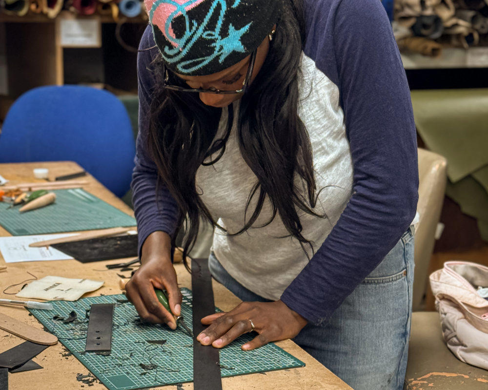 Person working on a craft project at a table with various tools and materials.