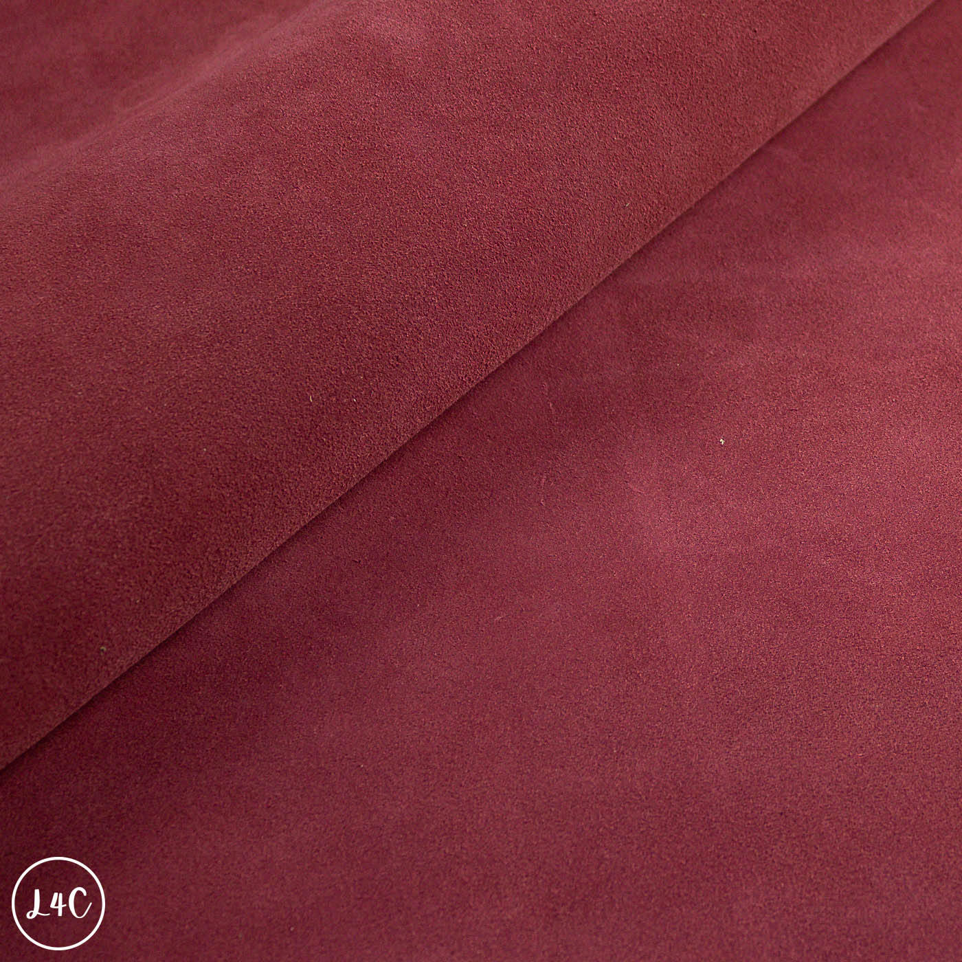 Close-up of maroon fabric with a visible brand logo in the corner.
