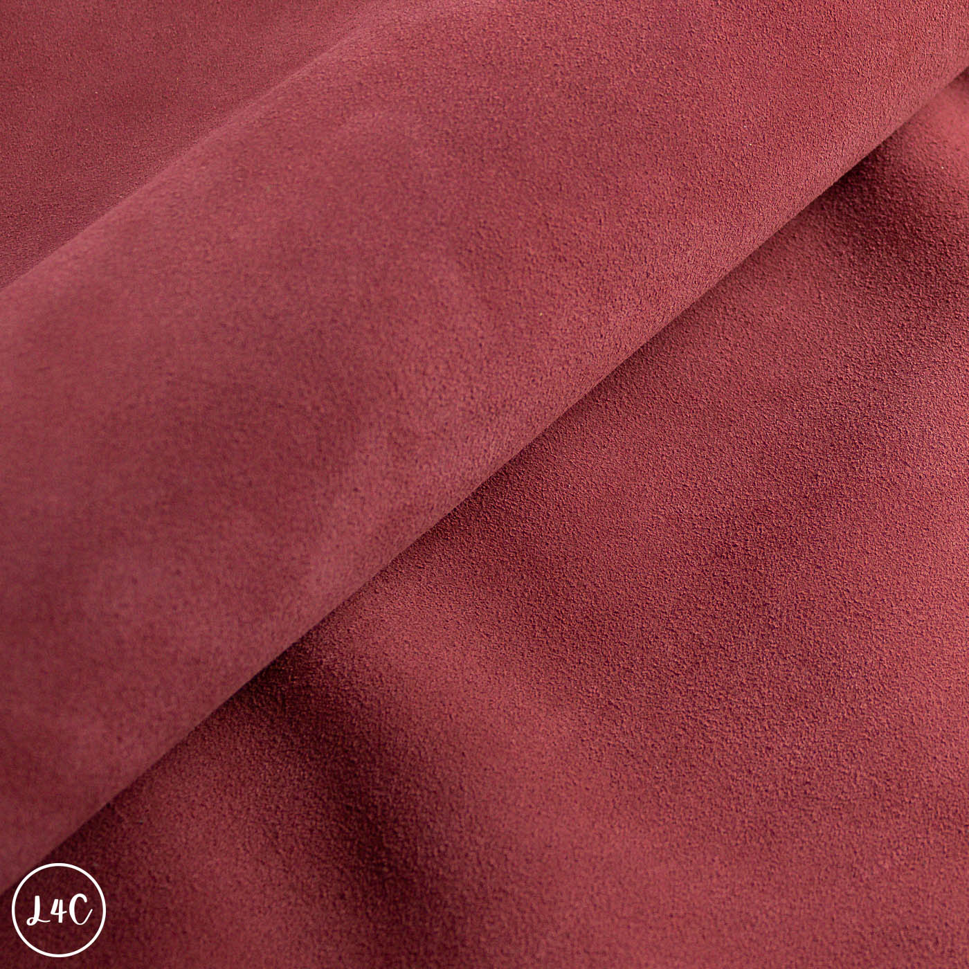 Close-up of red-brown suede with a visible brand logo in the corner.