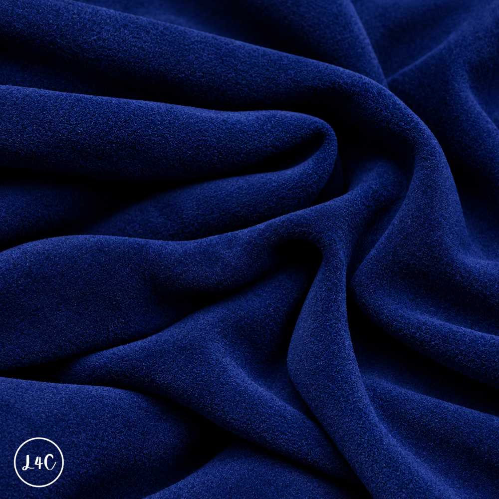 A close-up of draped blue navy suede leather with a soft, plush texture, showing deep folds and shadows.