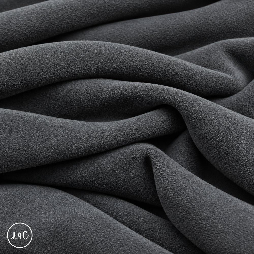 A close-up of draped grey suede leather with a soft, plush texture, showing deep folds and shadows.