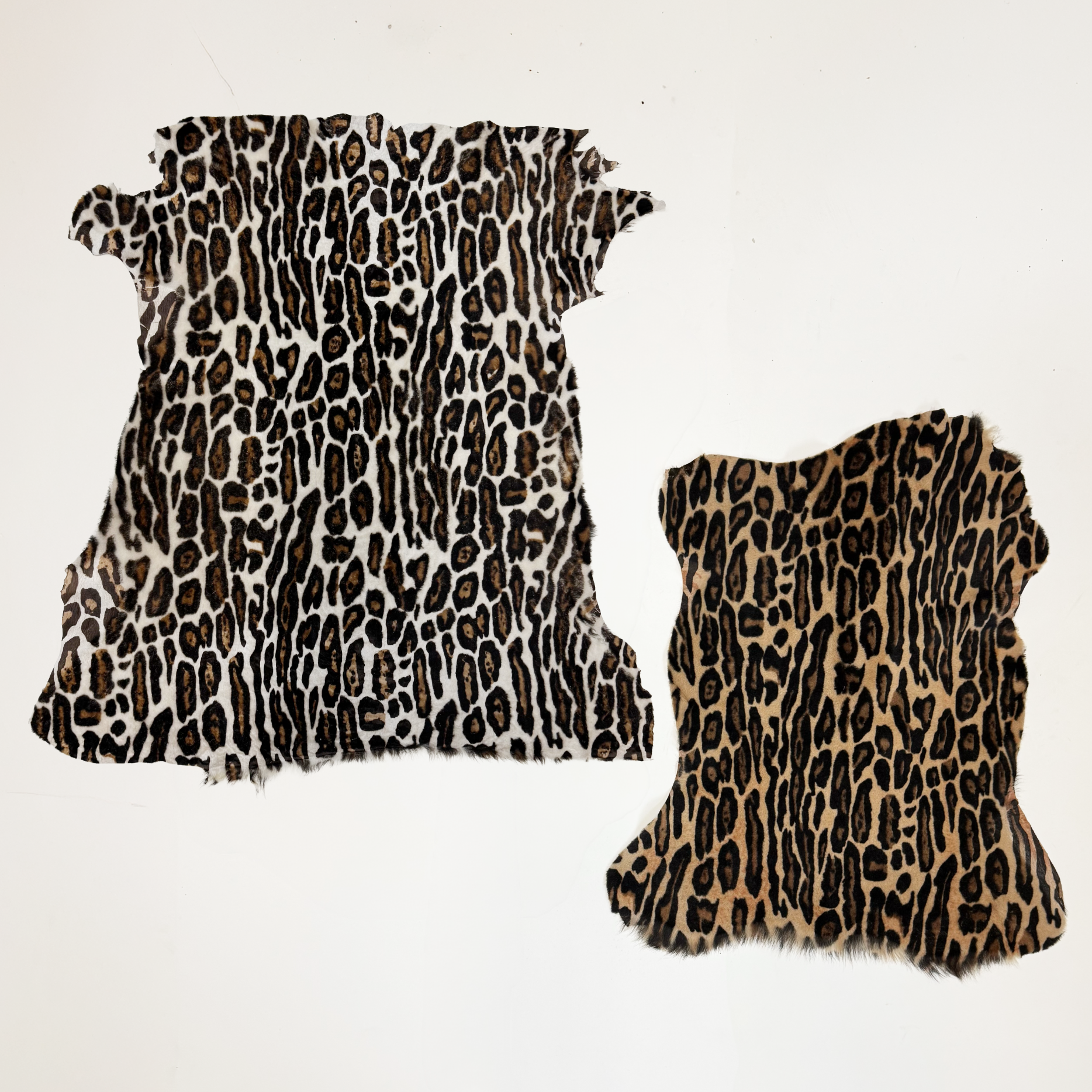 Two leopard print fabric leather hides on a white background