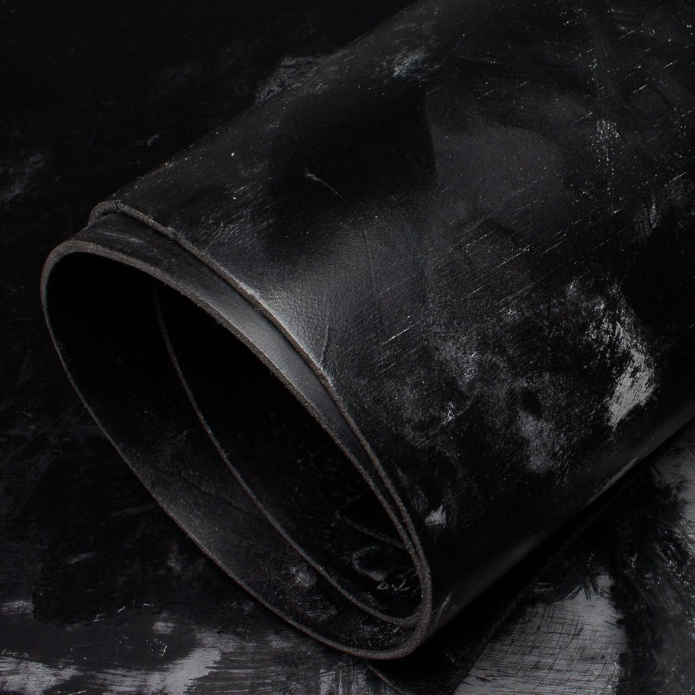 Roll of black bridle leather on a textured dark background