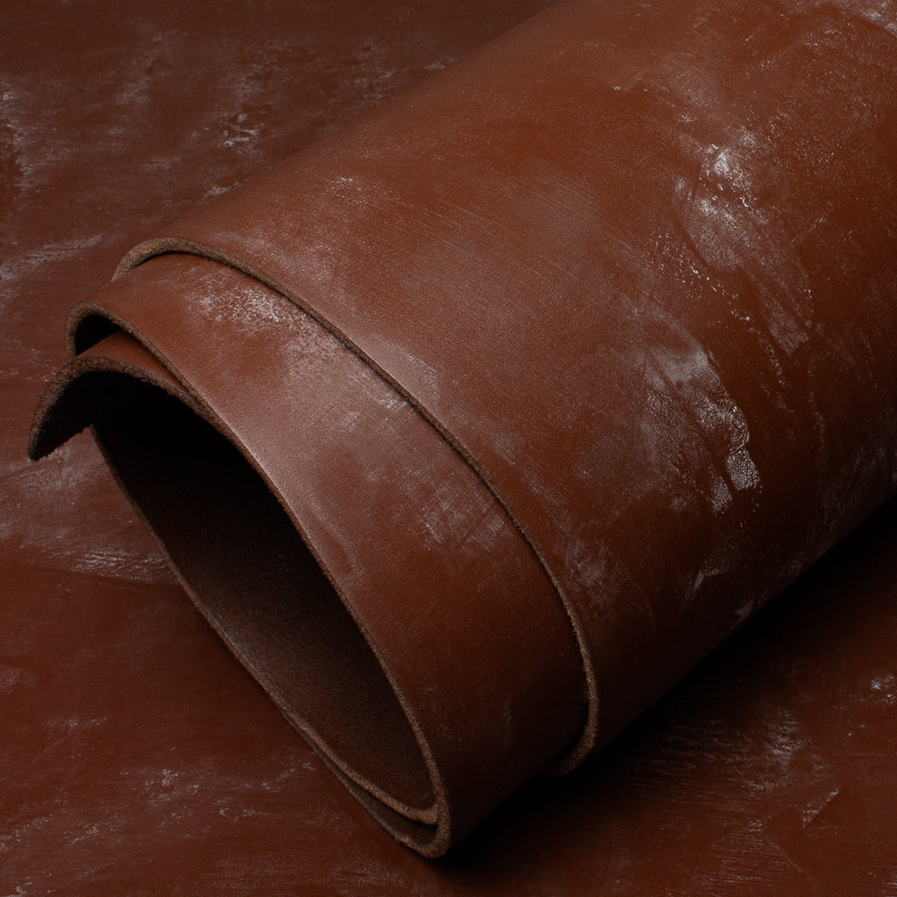 Rolled-up brown leather hide on a dark background
