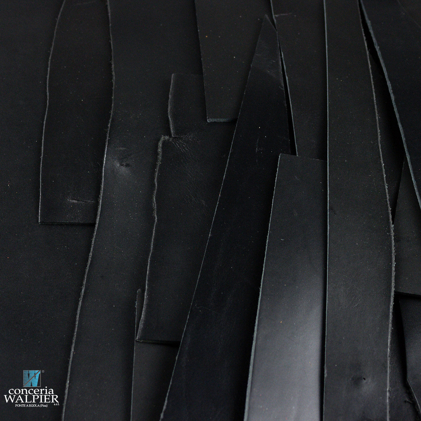 Close-up of black leather off cuts with a brand logo in the corner.