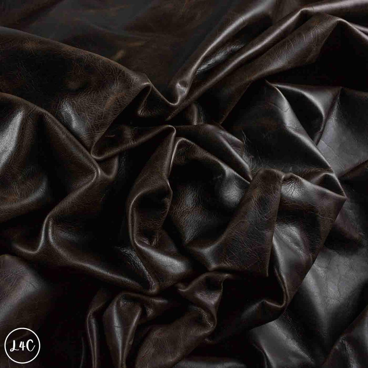 Dark brown textured leather fabric draped in soft folds, showing a glossy finish and fine grain texture.