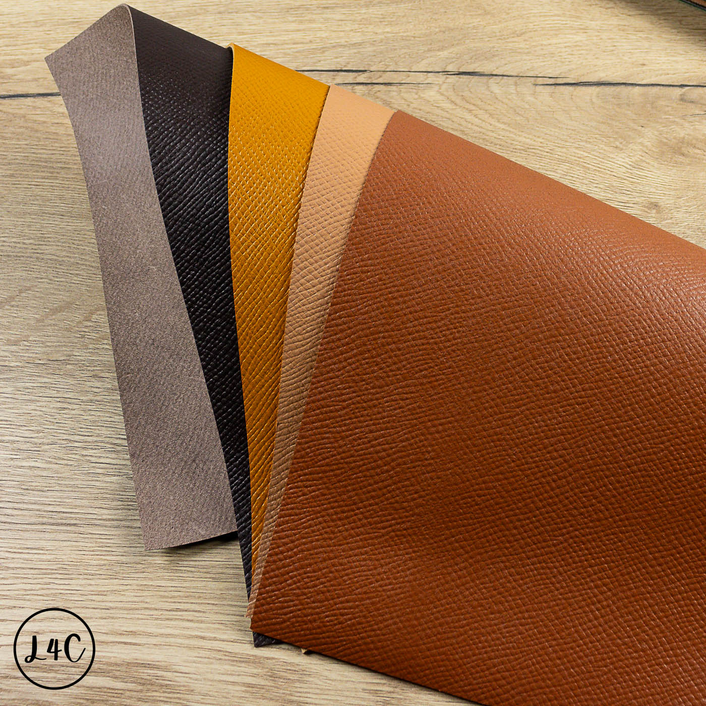 Four pieces of leather with different colors on a wooden surface