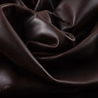 Close-up of dark brown leather fabric with folds