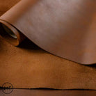 Close-up of brown leather fabric with a visible brand logo in the corner.