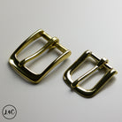 Two brass metal buckles on a gray background