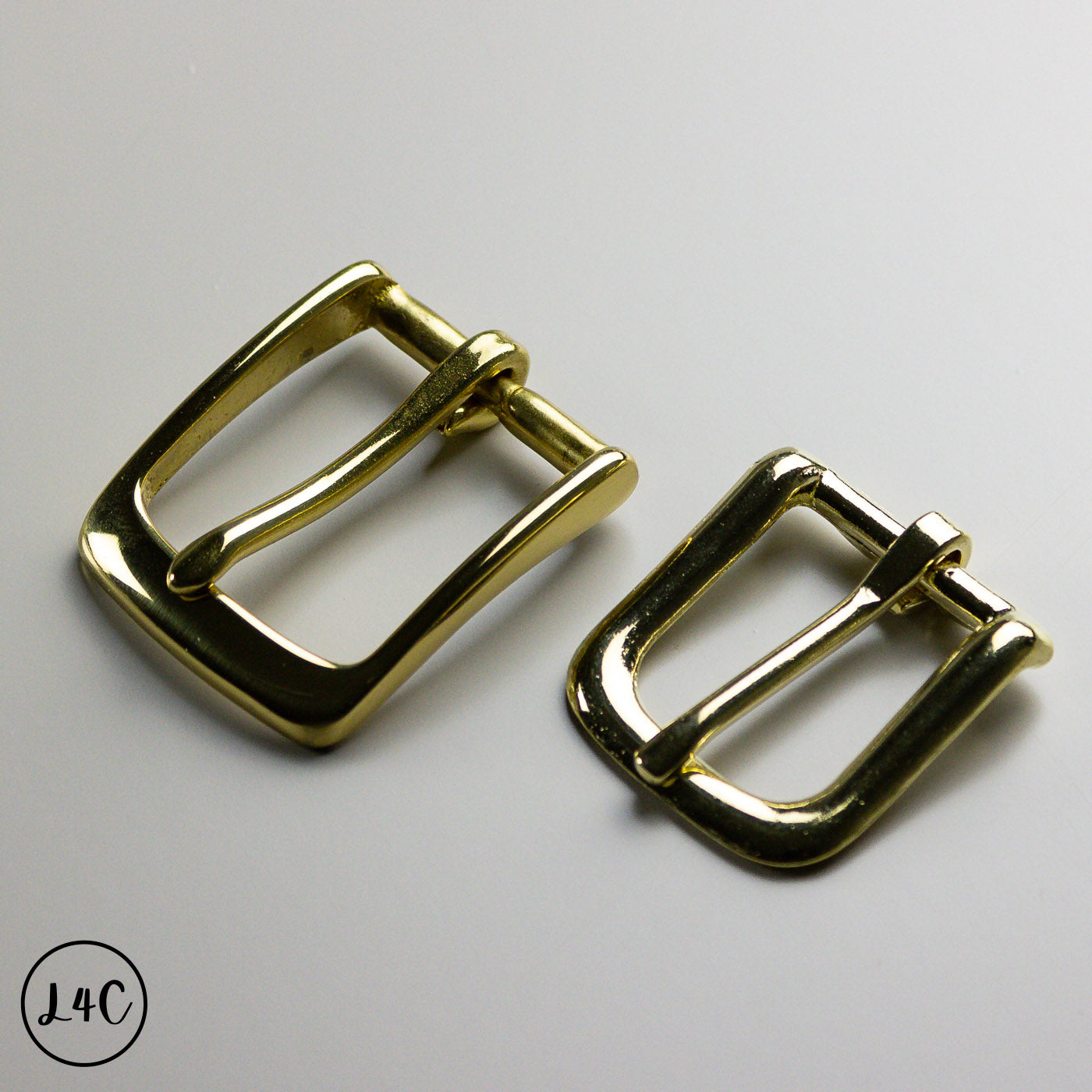 Two brass metal buckles on a gray background