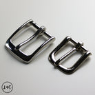 Two nickle metal buckles on a light gray background