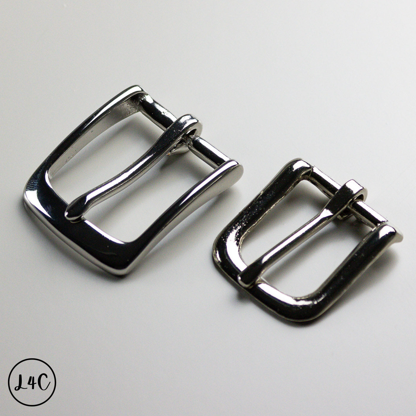 Two nickle metal buckles on a light gray background