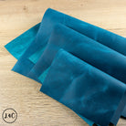 Three Turquoise leather sheets on a wooden surface
