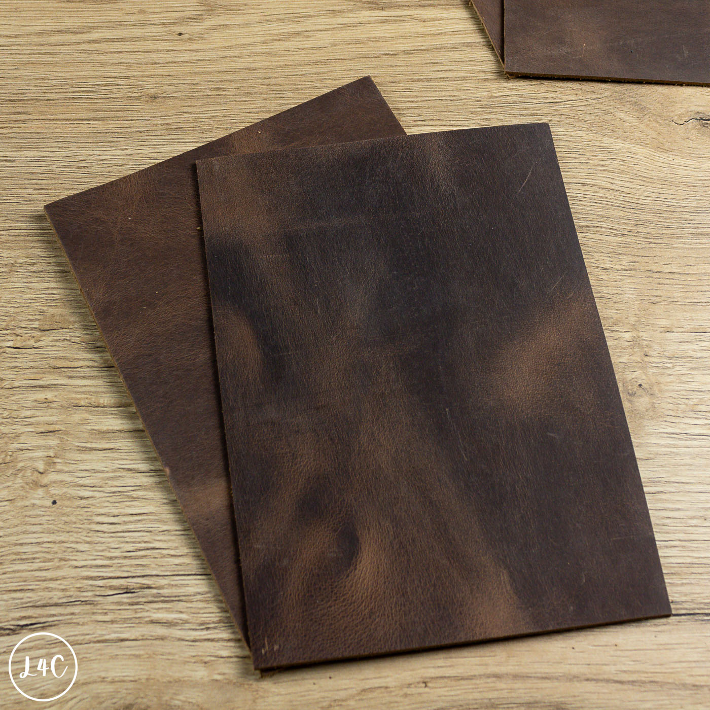 Two dark brown leather panels on a wooden surface