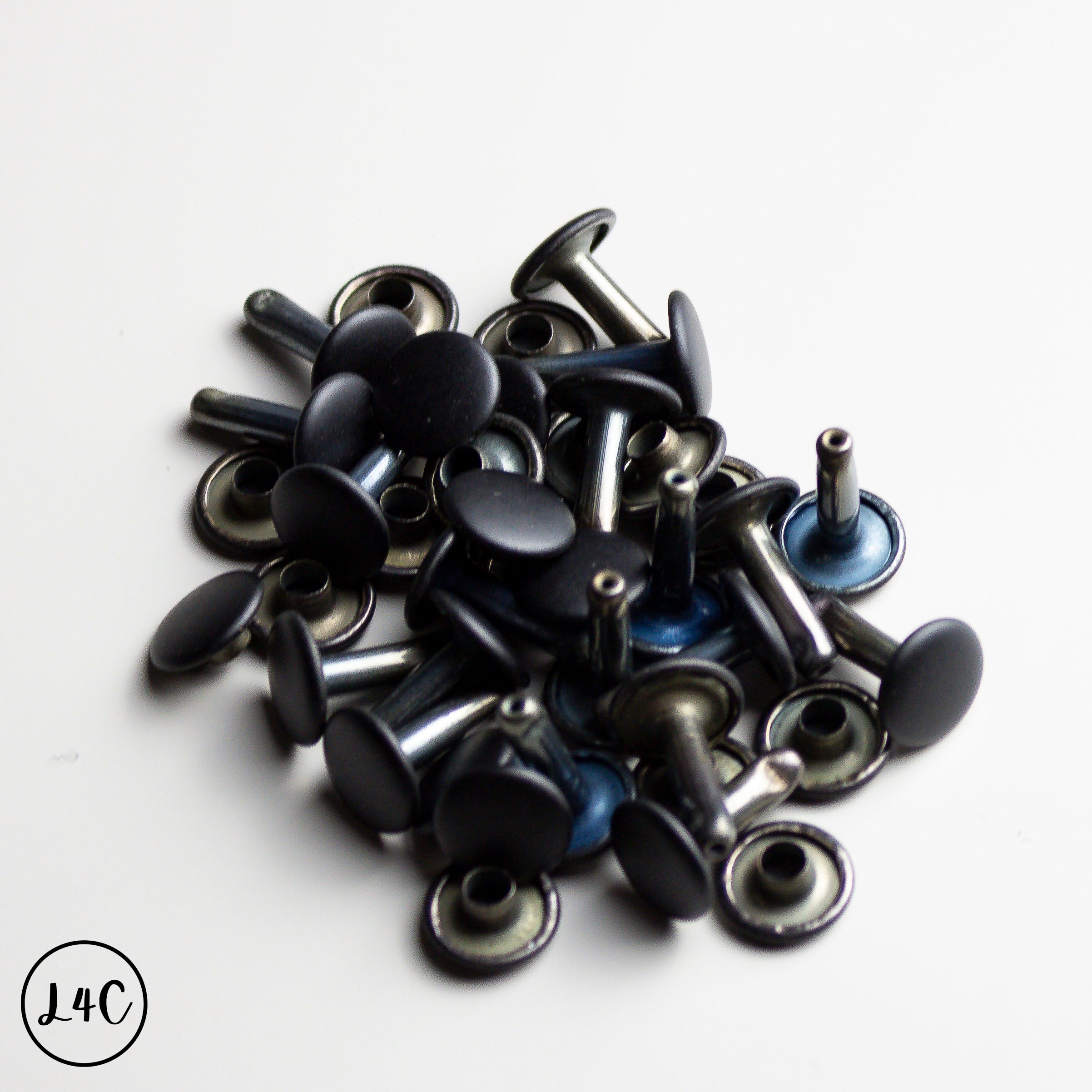 Collection of black and silver metal Double Cap Rivets on a white background
