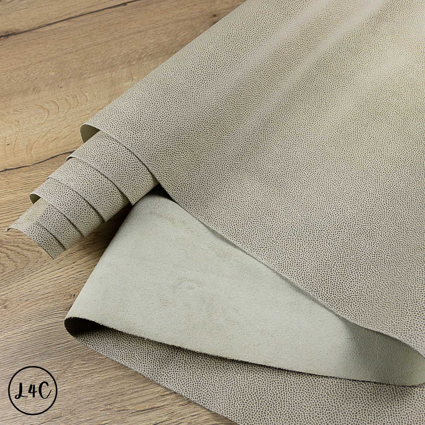 Roll of textured beige Tipped Epsom Grain Leather Hide on a wooden surface