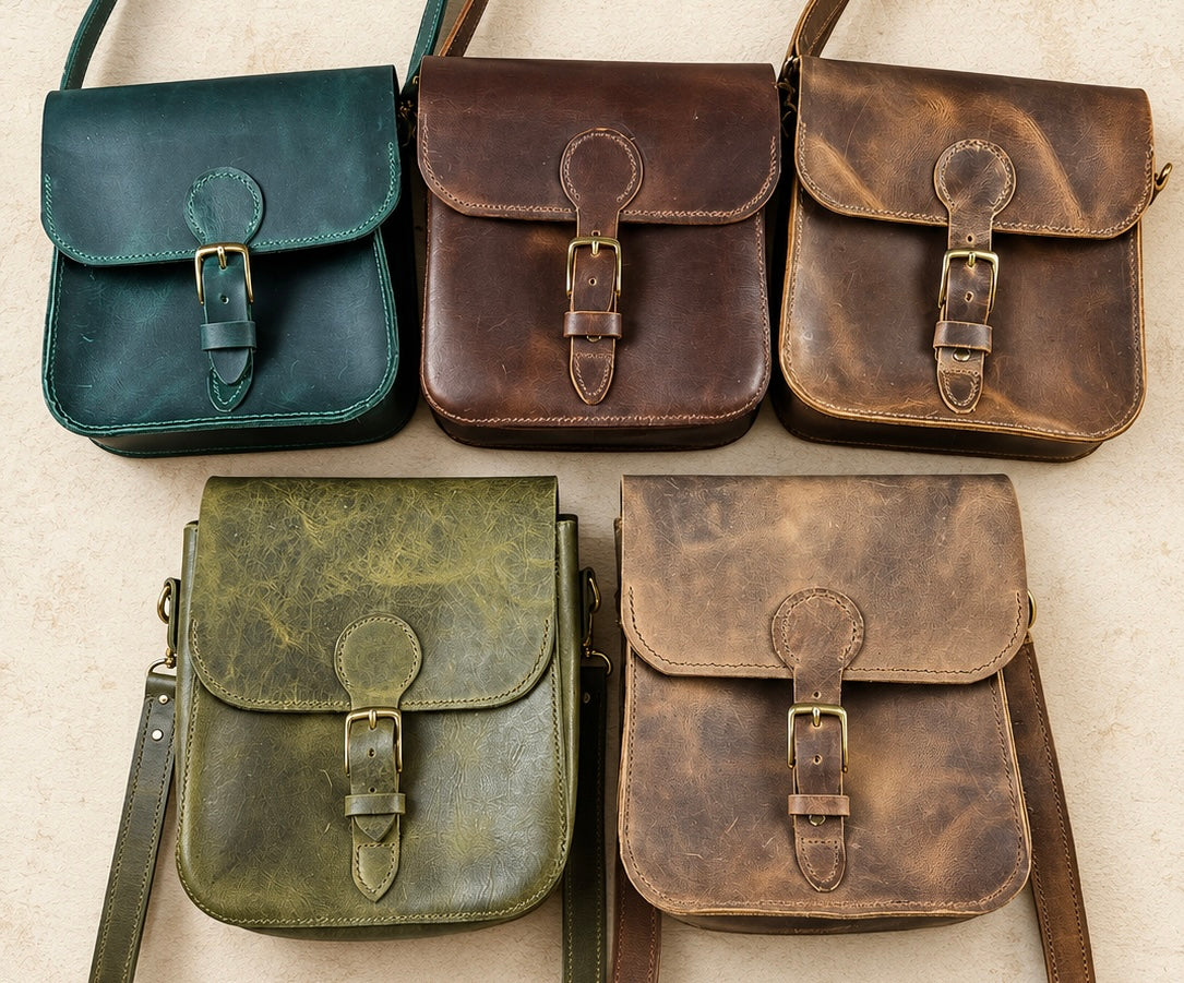 Five distressed leather satchel shoulder bags arranged in a 2x3 grid on a light beige textured background. The bags come in five different colors: dark teal, dark brown, cognac brown, olive green, and medium brown.
