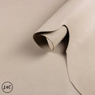 Beige leather sample with a visible crease on a beige background