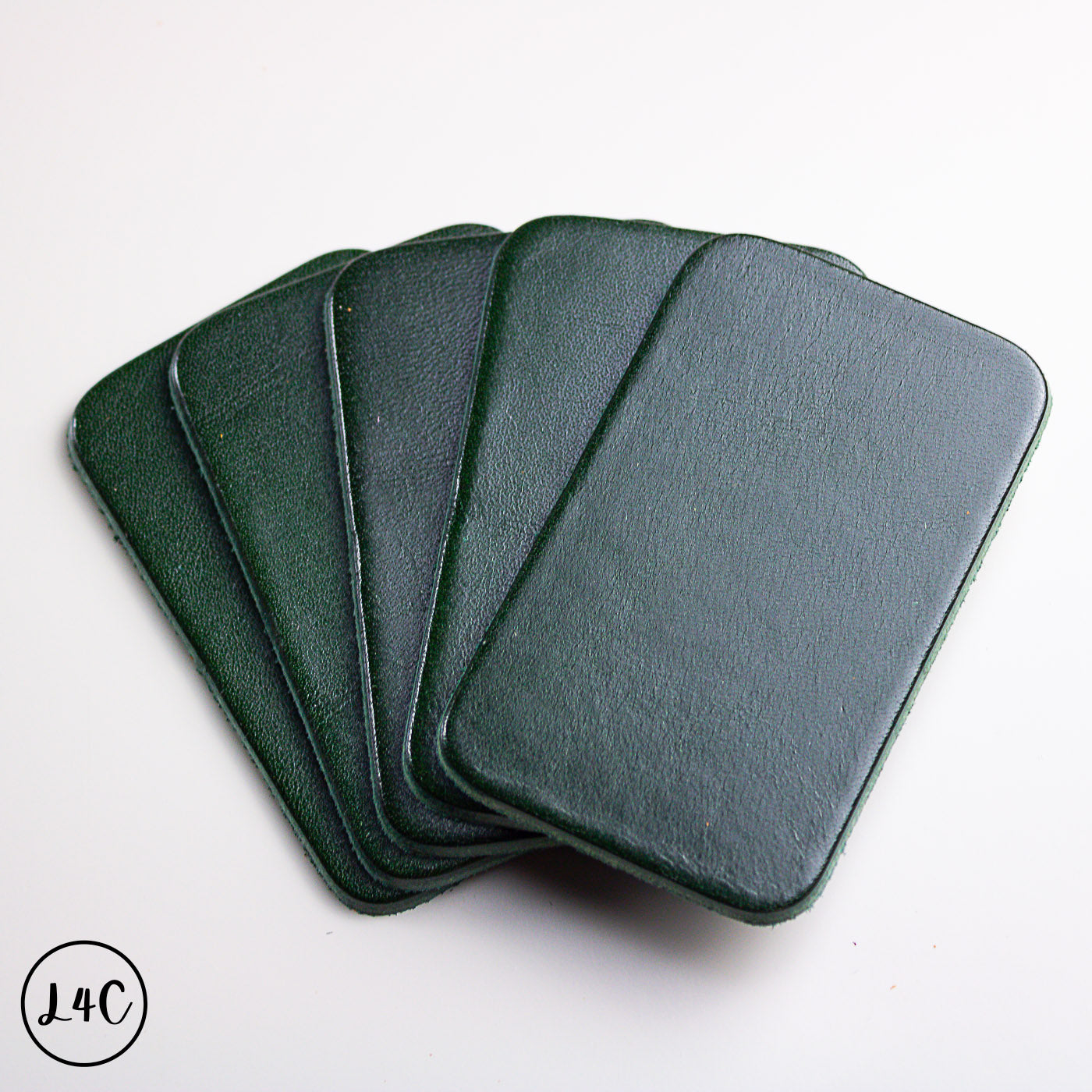 Set of five green leather labels stacked on a white background