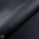 Close-up of black leather texture with a visible brand logo in the corner.