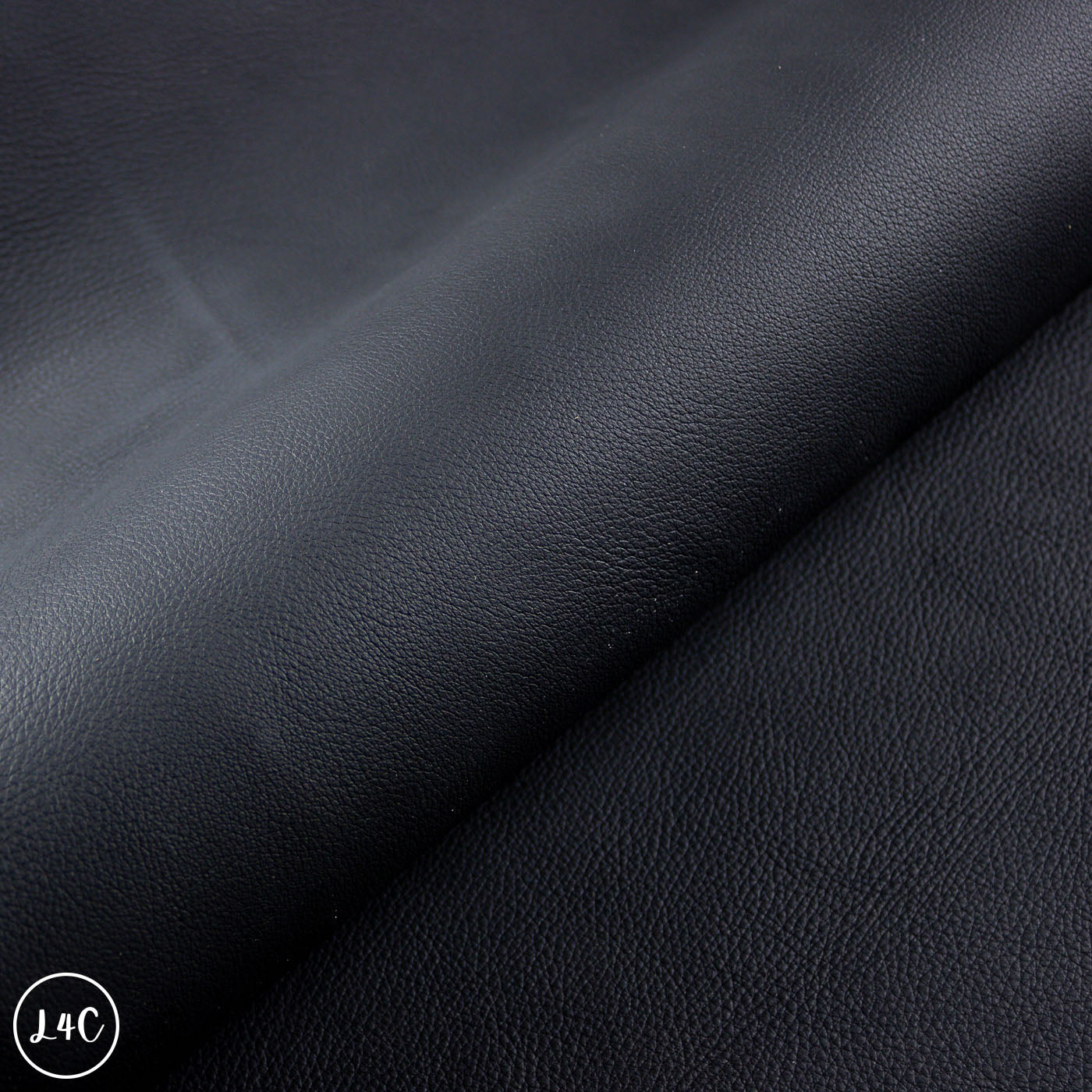Close-up of black leather texture with a visible brand logo in the corner.