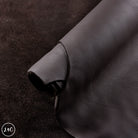 Close-up of black leather fabric with a visible brand logo in the corner.