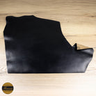 Black leather piece on a wooden surface with Horween logo.