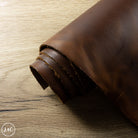 Rolled-up piece of brown leather on a wooden surface