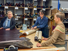 Three women working with leather rolls in a workshop setting.