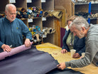 Three men examining leather in a workshop setting.
