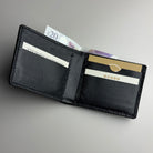 Black leather wallet with cards and money on a gray background