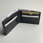 Black leather wallet with money and cards on a light gray background