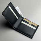 Black leather wallet with cards and money on a gray background