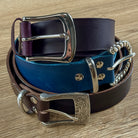 Three leather belts with metal buckles on a wooden surface