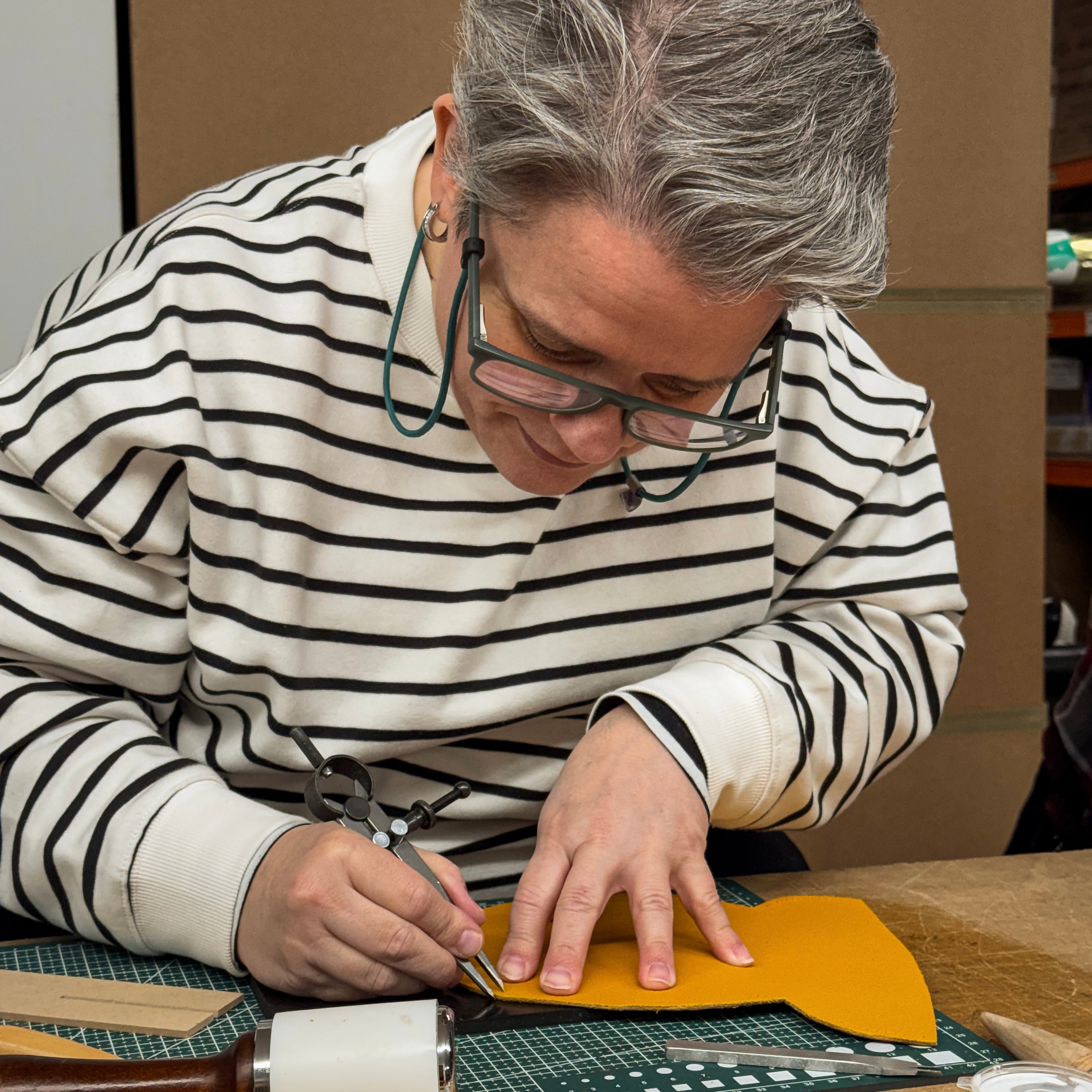 Person cutting leather with scissors on a table
