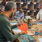 Group of people working together on a leather craft project in a workshop setting.